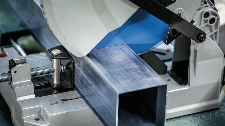 工业环境中，金属切割锯将大型钢梁切成薄片。.