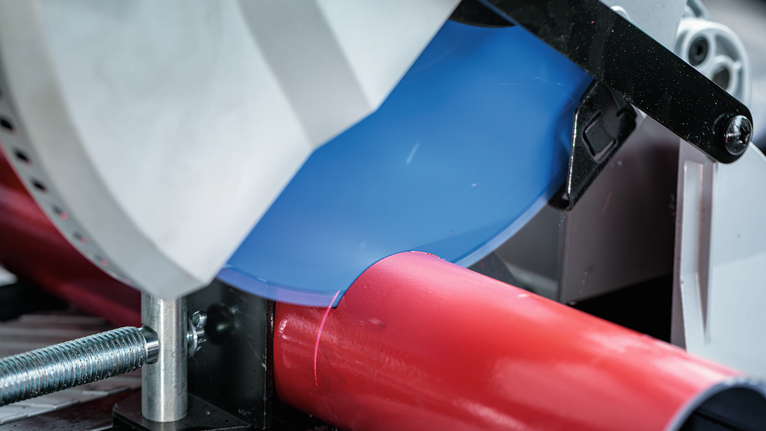 圆锯在车间环境中切割红色金属管。.