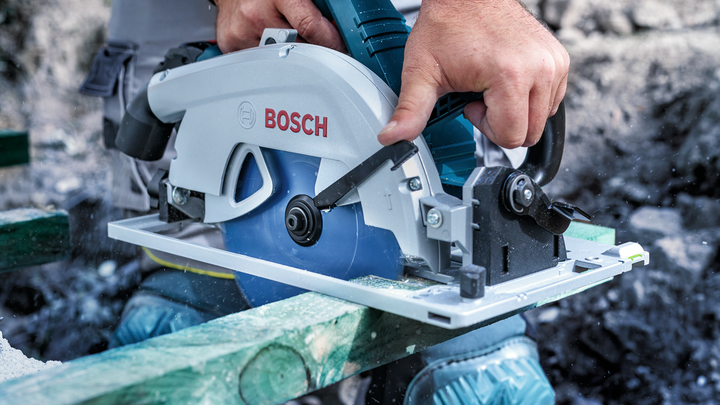 佩戴安全设备的人员使用圆锯切割木材。.