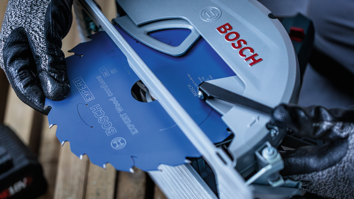 佩戴安全设备的人员将圆锯片安装到电动工具中。.