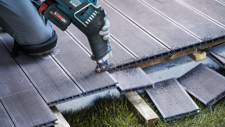 佩戴安全设备的人员使用电动工具切割复合地板。.