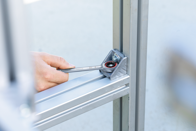 有人用棘轮扳手拧紧金属框架连接处的螺栓。