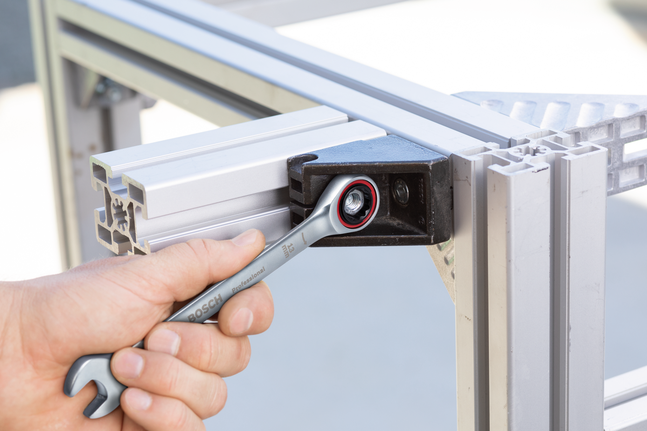 有人正在用棘轮扳手拧紧铝制框架上的螺栓。