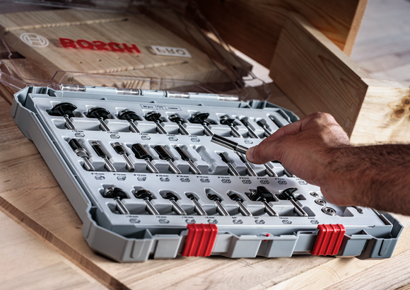 人们从木桌上整齐排列的钻头中选择一个钻头。.