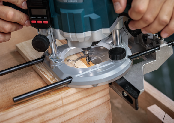 一个人使用凿子铣刀在一块木头上凿出凹槽。.