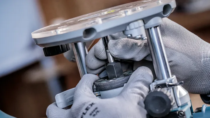 一名佩戴安全设备的人员在车间对电动工具进行一些调整。.