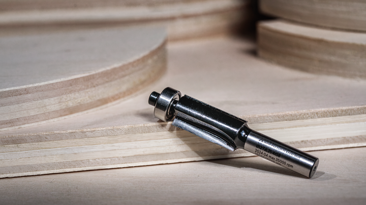 路由器钻头放置在堆叠的胶合板附近的木质表面上。.