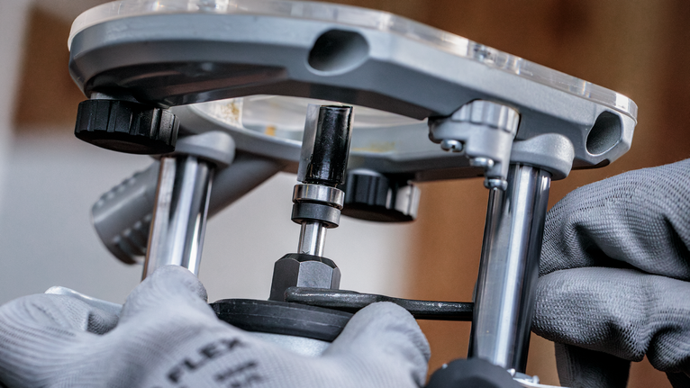 佩戴安全设备的人员正在调整金属路由器工具。.