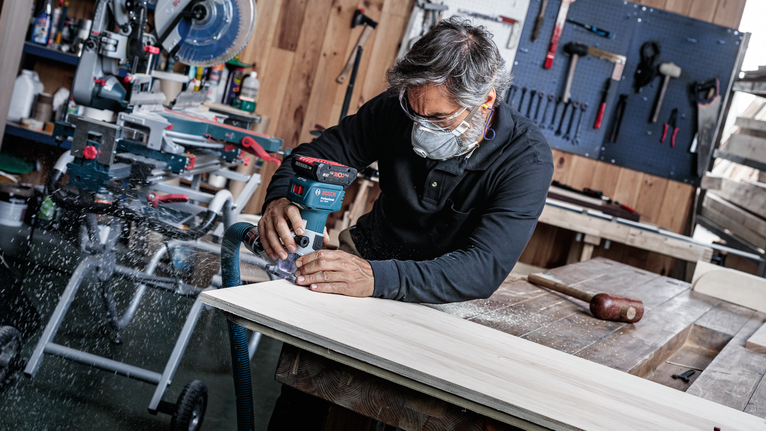 一名佩戴安全设备的人在木板上使用无绳路由器。.