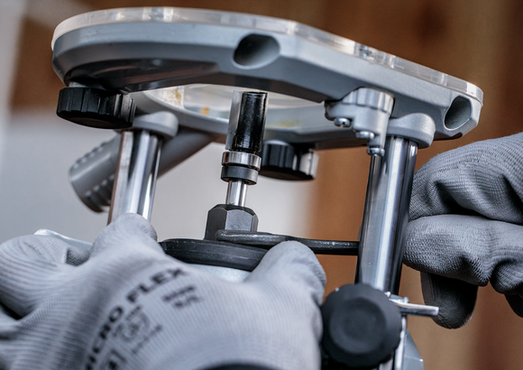 佩戴安全设备的人员用扳手调整电动工具。.