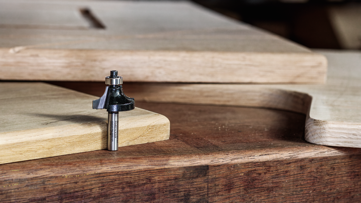 路由器钻头放在木制工作台上，旁边是切割和成型的木板。.