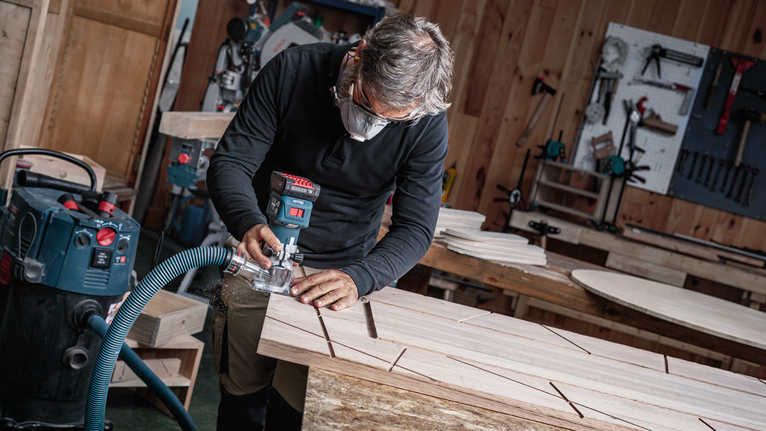 佩戴安全设备的人员使用电动工具在木板上开槽。.