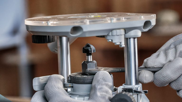 佩戴安全设备的人员使用扳手调整路由器工具。.