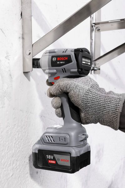 一名佩戴安全设备的人员使用无绳冲击扳手紧固金属支架。.