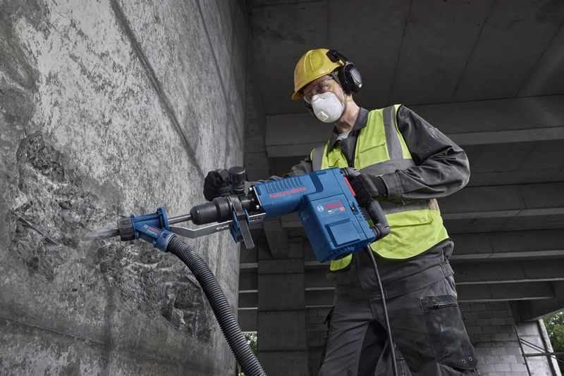 一名佩戴安全设备的人员操作破碎锤对混凝土墙进行破碎。.