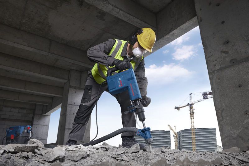 一名佩戴安全设备的人员操作破碎锤处理混凝土碎片。.