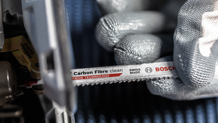 佩戴安全设备的人员将碳纤维锯片安装到电动工具中。.