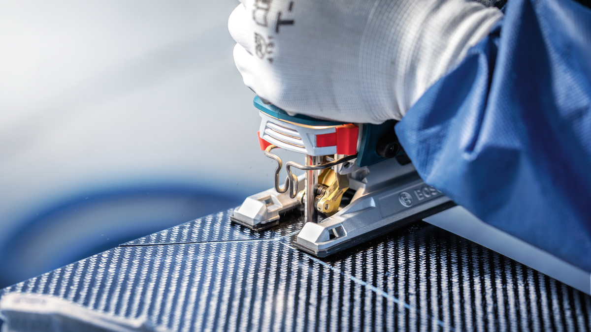 佩戴安全设备的人员使用拼图锯切割有图案的面板。.