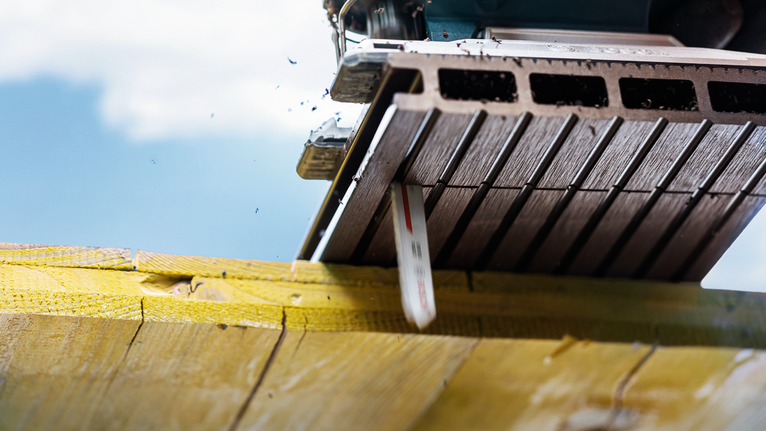 在明亮的室外灯光下，锯片切割木梁。.