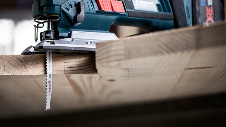 车间里，拼图锯正在切割一块厚木板。.