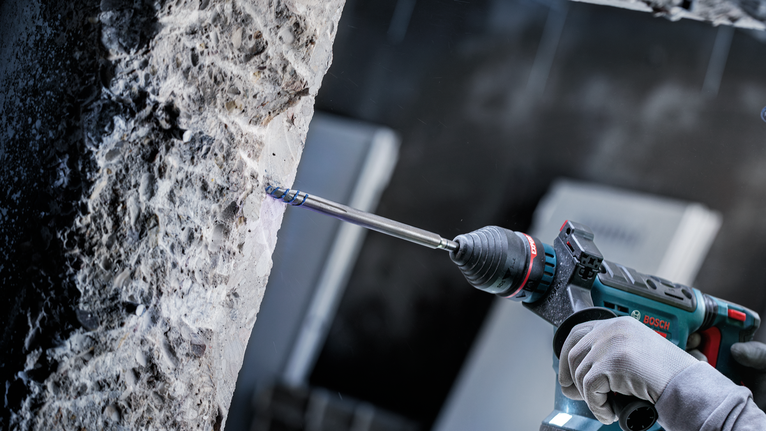 佩戴安全设备的人员使用电动工具钻入混凝土。