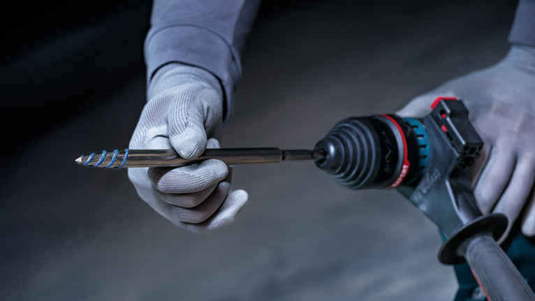 佩戴安全设备的人员将钻头插入电动工具。