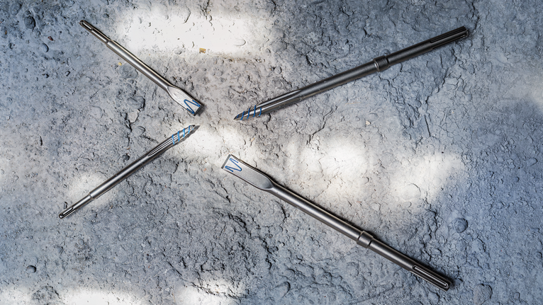 四个金属钻头排列在粗糙的混凝土表面上。