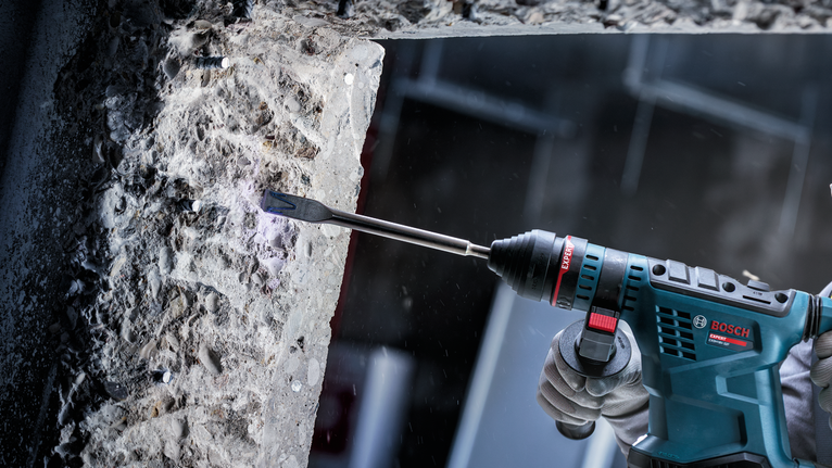 佩戴安全设备的人员使用电动工具凿碎混凝土。