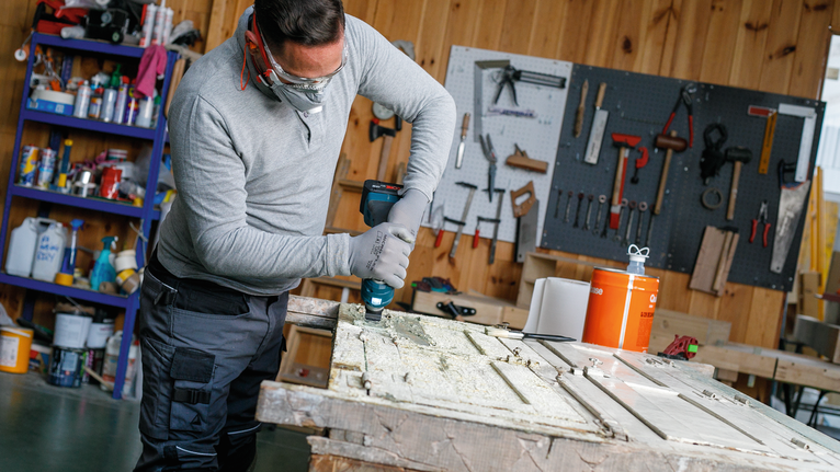 一名身穿安全设备的人员正在车间钻木门。