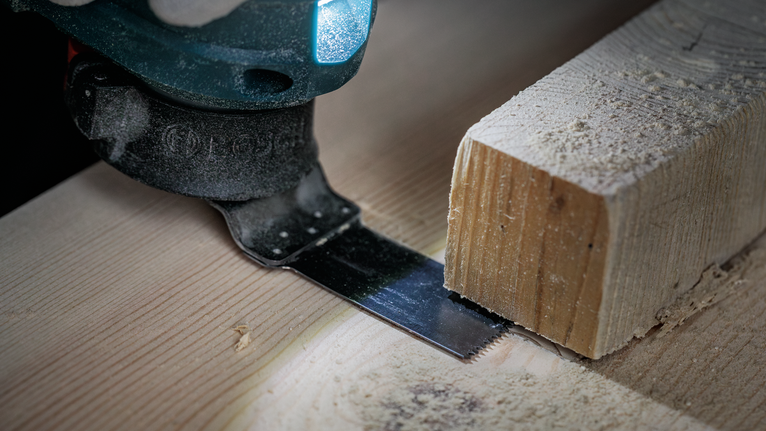 车间近景镜头：往复锯片正在切割木板。