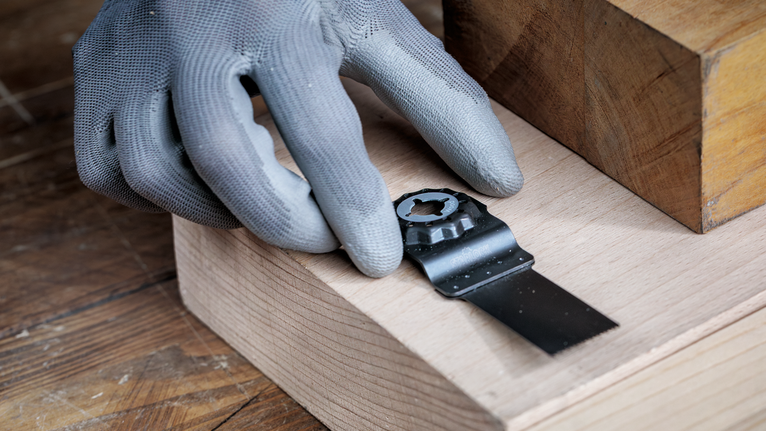 佩戴安全装备的人员将金属锯片安装到木质表面上。