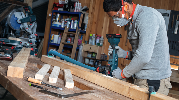 一名佩戴安全设备的人员在车间内钻木梁。