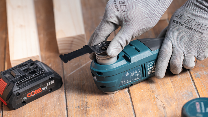 佩戴安全设备的人员在木制工作台上调整多功能工具。