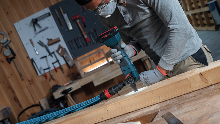 一名佩戴安全设备的人员在车间内钻木梁。