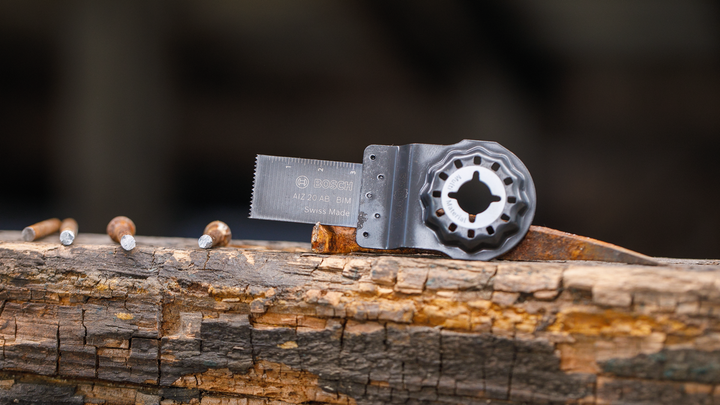 振荡锯片附件用钉子放置在风化的木梁上。