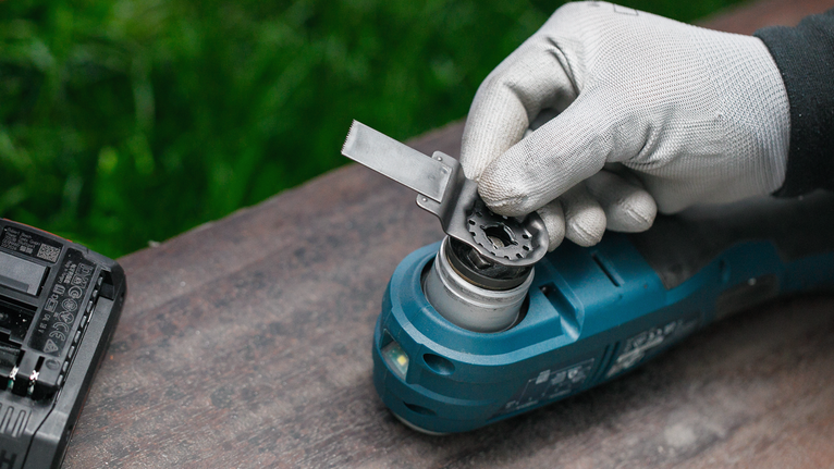 佩戴安全设备的人员将刀片安装到蓝色电动工具上。