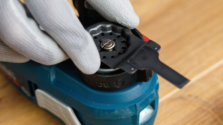 佩戴安全设备的人员在蓝色电动工具上安装刀片。