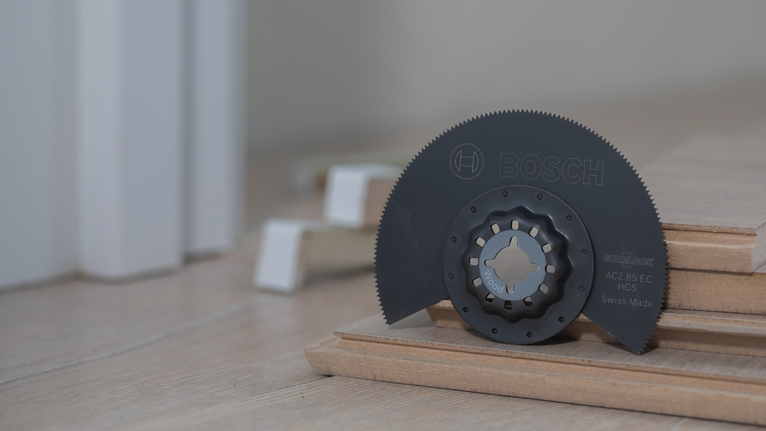 振荡多功能工具刀片放置在堆叠的木板上。