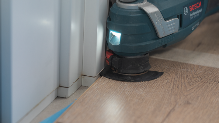 使用多用途振动工具切割墙角附近的复合地板。