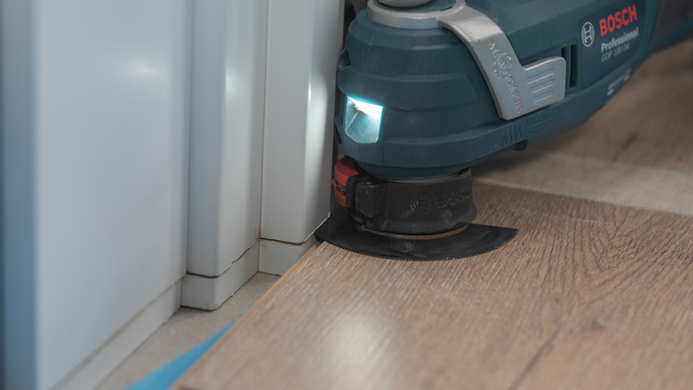 使用多用途振动工具切割墙角附近的复合地板。