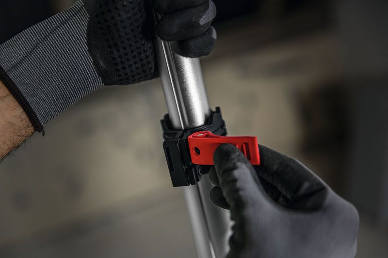 一名佩戴安全装备的人员正在调整金属杆上的红色夹子。