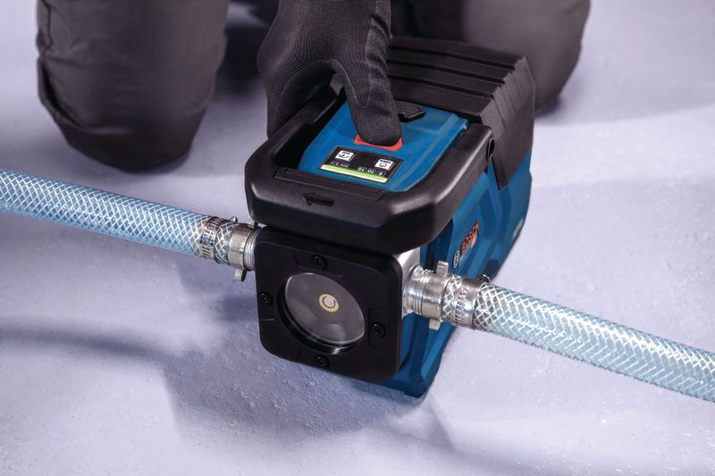 一名佩戴安全装备的人员操作着连接软管的便携式水泵。