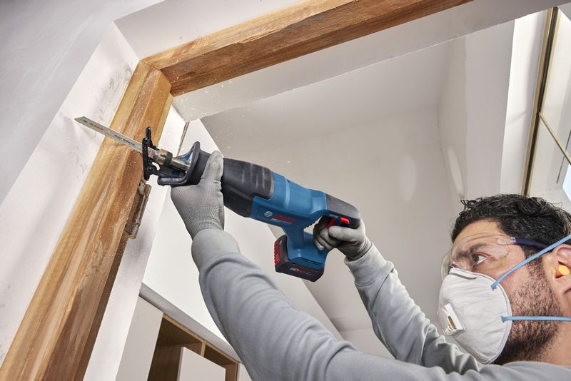 一名佩戴安全装备的人员使用无绳往复锯切割门框。