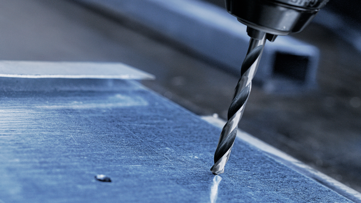 用钻头在金属板上钻孔。