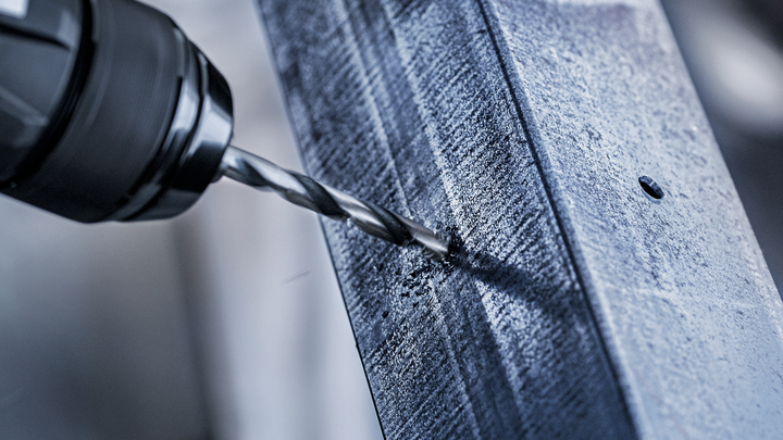 电钻在金属梁上钻出一个孔。