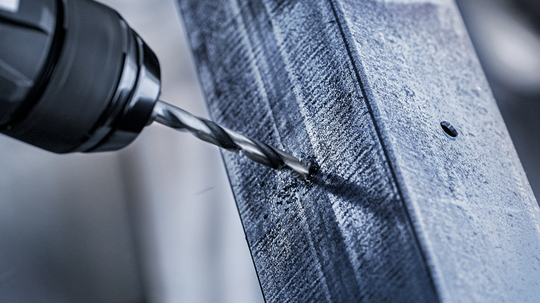 电钻在金属梁上钻出一个孔。