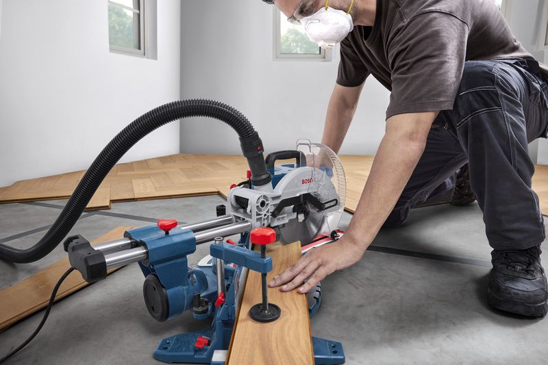 一名佩戴安全装备的人员正在用斜切锯切割木地板。