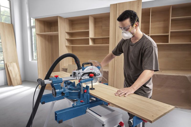 一名佩戴安全装备的人员使用斜切锯切割木板。