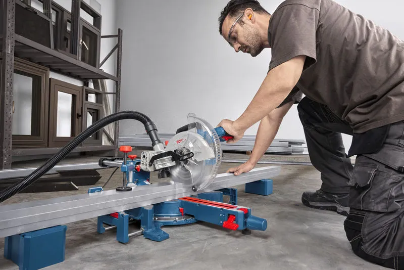 一名佩戴安全装备的人员正在使用斜切锯切割金属梁。