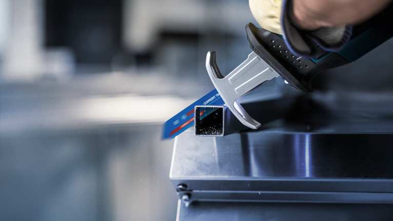 一名佩戴安全装备的人员使用往复锯切割金属方管。